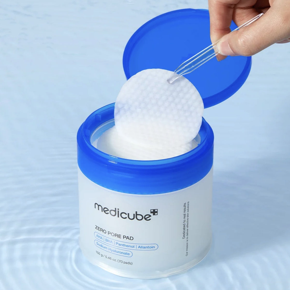 Frasco de Medicube Zero Pore Pad 2.0 abierto, sacando un disco con la pinza
